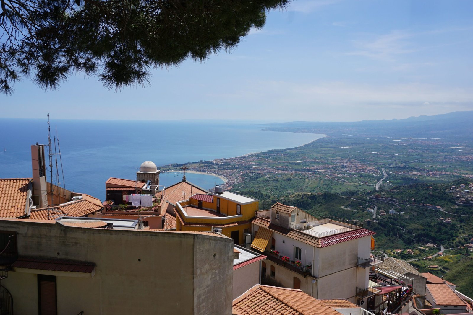 Sicilian rooftops and coastline under a bright summer sky